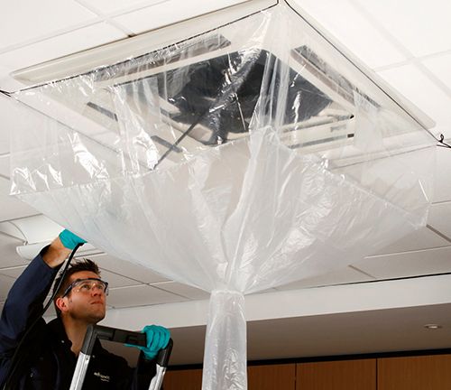 man die een airco-plafondunit proper maakt